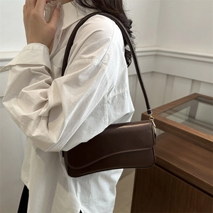 Deep brown leather crossbody bag with magnetic flap and gold hardware on white background
