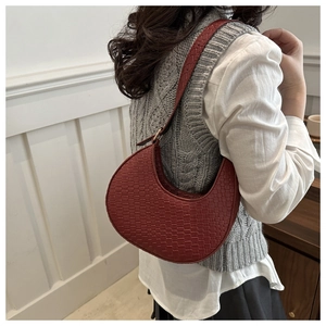 Close-up of deep red crescent underarm bag featuring a stylish woven texture and adjustable strap