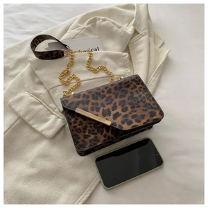 Detail of leopard print crossbody bag with gold chain strap and textured flap finish