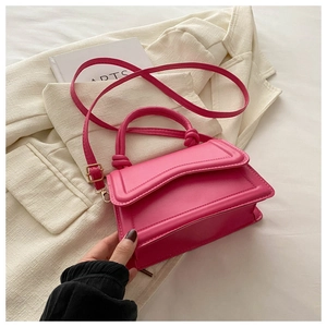 Detail of rose red PU leather handbag with decorative knot handles and fine shoulder strap