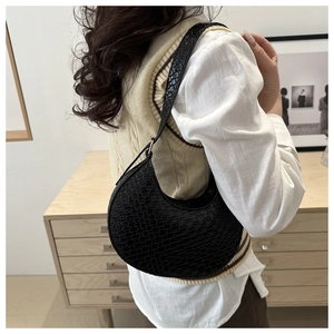 Detail of black faux leather hobo bag with crocodile pattern and golden hardware