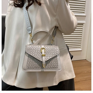 Close-up of silver woven texture handbag with gold buckles and grey shoulder strap