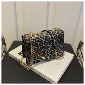 Close-up of leopard print shoulder bag with gold chain strap on a white book
