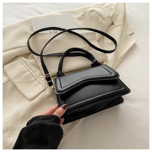 Detail of elegant black crossbody bag with wavy flap design and gold hardware accents