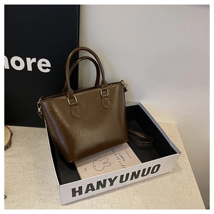 Detailed view of dark brown oil wax leather tote bag with gold-tone hardware and straps