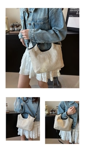 Detail of a beige woven straw tote bag with black leather trim and gold metal buckles