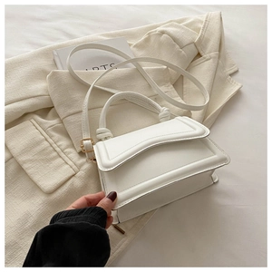 Detail of white PU leather square handbag with fine stitching on a white blazer