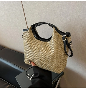 Detail of hand-woven straw tote bag with black leather trim and gold-tone metal hardware