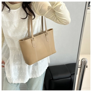 Detail of khaki leather tote bag with white contrast stitching and golden hardware