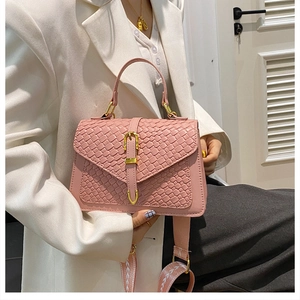 Pink woven texture handbag with gold hardware and wide shoulder strap on model