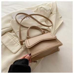 Close-up of beige faux leather bag with wavy stitching and gold metal hardware detail