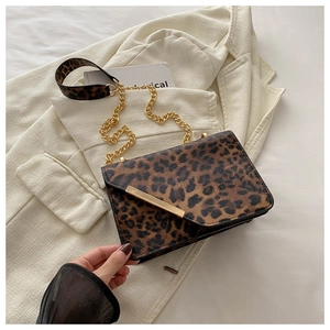 Detail of leopard print crossbody bag with golden chain strap and stylish metal bar buckle