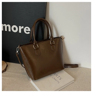 Detail of dark brown leather tote bag with gold hardware on a minimalist background