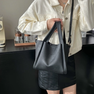 Litchi pattern black leather tote bag with FASHION lettering shown in a cafe setting