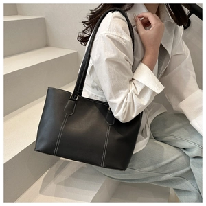 Detail of black tote bag with white contrast stitching on model with casual outfit