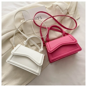 Detail showing white and fuchsia mini crossbody bags with knotted handles and flap covers