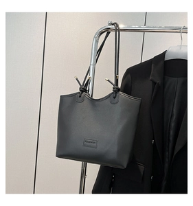 Detail view of black PU tote bag with FASHION leather patch and gold metal accents