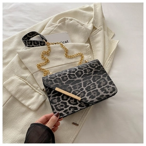 Detail of leopard print crossbody bag with gold chain strap and textured leather finish