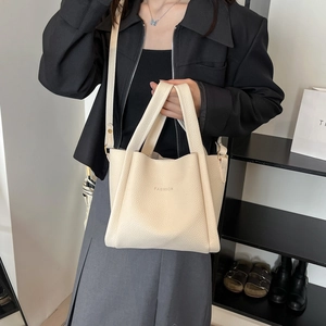 Minimalist beige lychee grain bucket bag with FASHION text and gold hardware