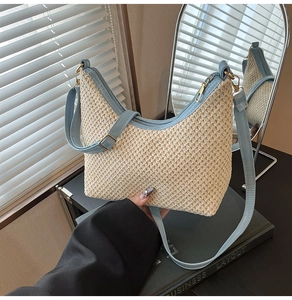 Close-up of woven straw handbag with light blue leather trim and secure zipper detail
