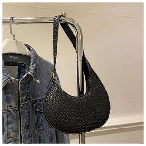 Detail of black faux leather hobo bag with crocodile pattern and woven shoulder strap