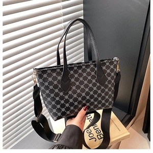 Detail of black tote bag featuring white geometric chain patterns and gold metal hardware