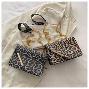 Detail of leopard print crossbody bags with golden chain straps on white suit jacket