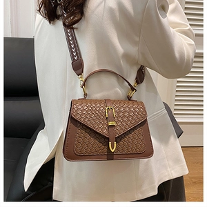 Brown woven crossbody bag featuring a patterned strap and gold buckle detail