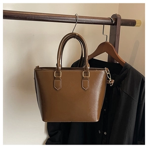 Detail of dark brown retro tote bag with lychee texture and golden metal hardware