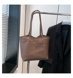 Close-up of a large tan PU leather tote bag featuring a front pocket and long shoulder strap