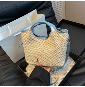 Detail of woven straw tote bag with light blue leather trim and detachable shoulder strap