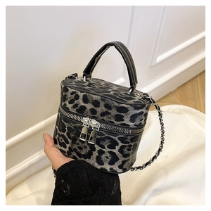 Macro view of leopard print texture on cylindrical crossbody bag with silver chain