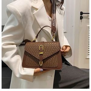 Detail of a brown woven texture crossbody bag with gold buckle and geometric strap