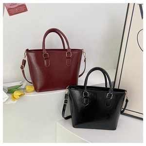 Close-up of vintage bucket bags in burgundy and black with glossy finish and gold hardware