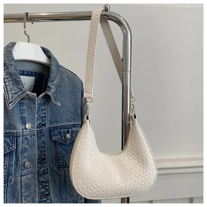 Detalle de bolso hobo trenzado blanco con correa de cocodrilo y hebilla metálica dorada