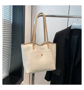 Detail of minimalist tote bag with contrast brown straps and front pocket detail