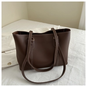 Detail of dark brown tote bag featuring contrast white stitching and fine leather texture
