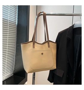 Detail of beige leather tote bag with brown straps and large front pocket detail