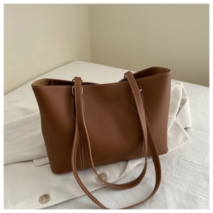 Close-up of brown tote bag with contrast white stitching and minimalist PU leather texture