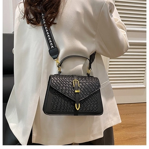 Close-up of black leather crossbody bag with woven detail and gold metal hardware