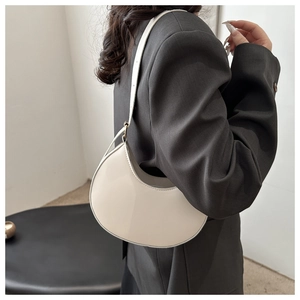 Detail view of the cream-white crescent shoulder bag with fine stitching and gold hardware