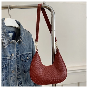 Primer plano detallado del bolso hobo de tejido burdeos con herrajes dorados