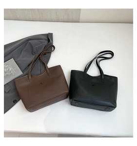 Detail of minimalist coffee and black tote bags with front flap pockets and matte leather