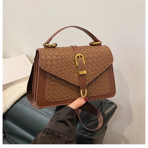 Detail showing deep brown woven texture and gold buckle on a retro crossbody bag