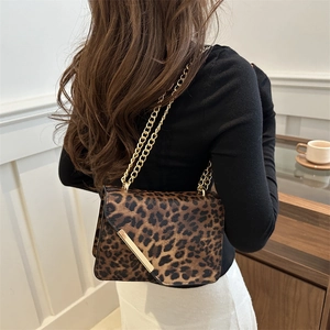 Leopard print crossbody bag with gold chain strap shown on a model in a modern interior