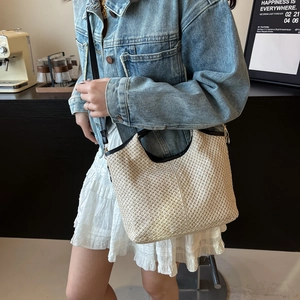 Chic woven beach tote bag in off-white straw with black leather straps and large capacity