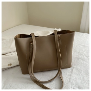 Close-up of tan leather tote bag with white contrast stitching and minimalist design