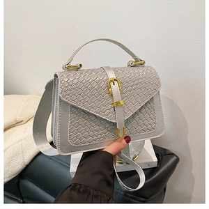 Detailed view of grey woven texture handbag with golden buckle and wide fabric strap
