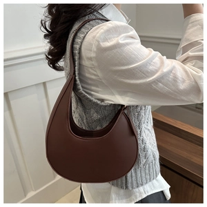 Side view of a vintage dark brown crescent shoulder bag worn on a model in a warm interior