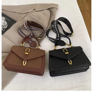 Close-up of woven texture handbags in black and brown with geometric patterned wide straps